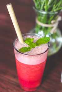 drinking glass with pink beverage and mint leaves